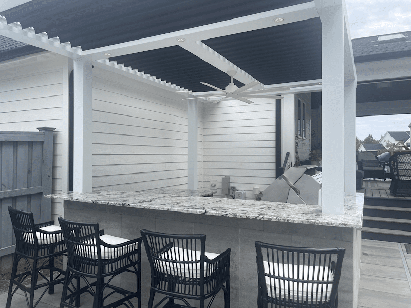 StruXure Pergola providing shade for an outdoor kitchen and dining area.