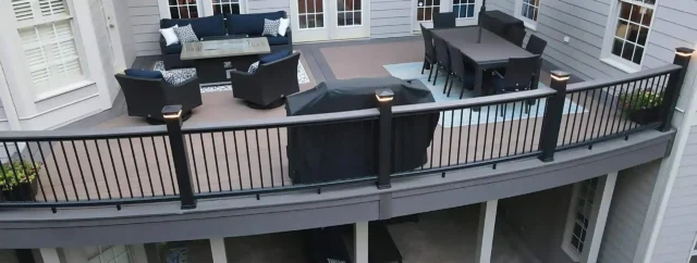 photo of an elevated composite deck with outdoor furniture and patio below - Composite decking cost