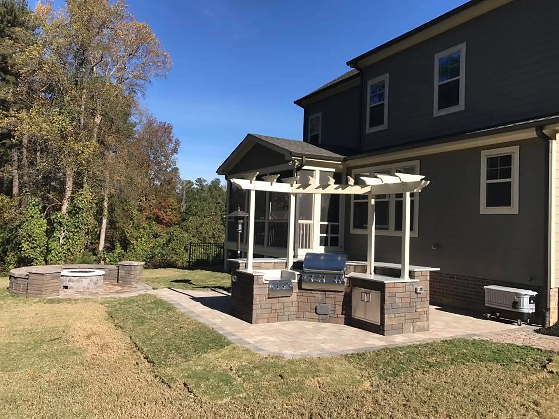 photo of outdoor kitchen, pergola, patio, and a fire pit with built-in seating wall