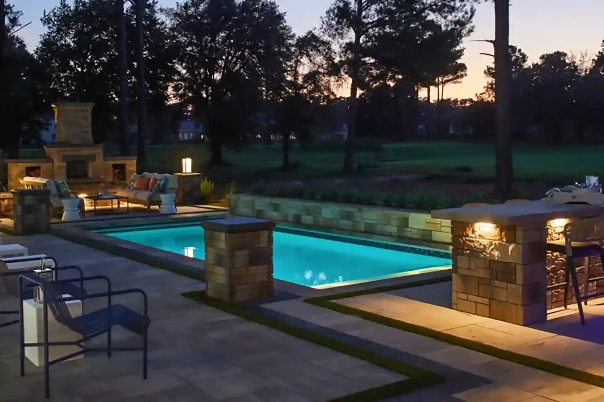 photo of a paver project by Majestic Outdoors showing the paver pool deck, columns, and outdoor lighting
