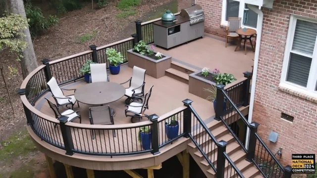 Photo of an elevated multi-level deck with a curved outdoor dining area, a grilling station, deck railing, and deck steps
